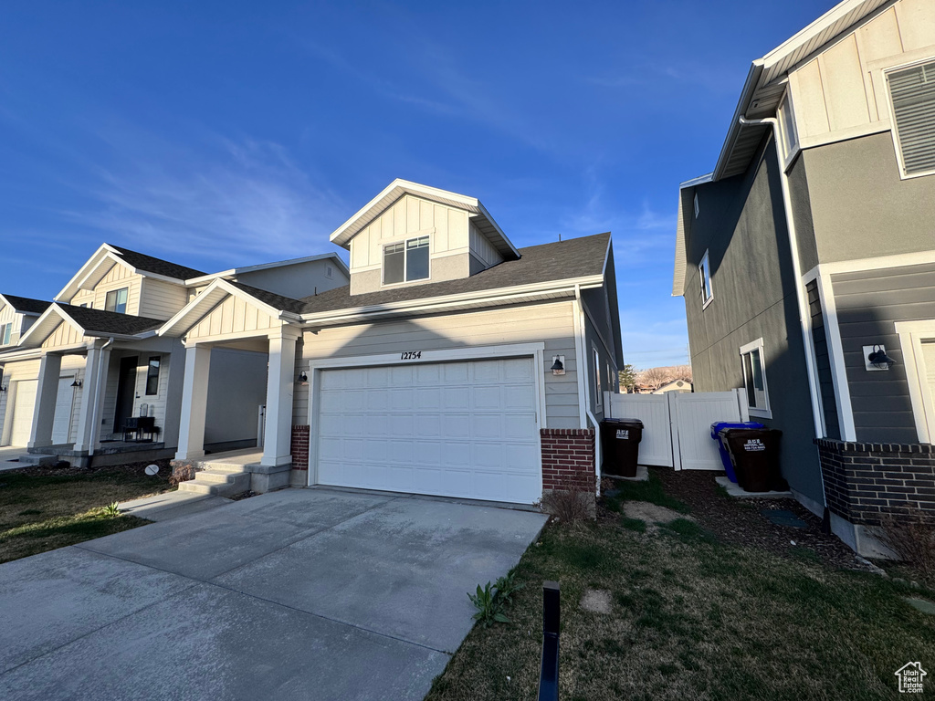 View of front of house with board and batten siding, concrete driveway, and fence