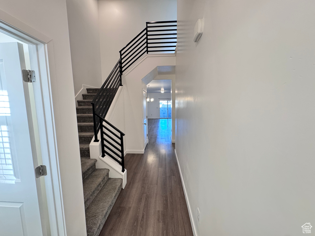 Corridor with stairs, a high ceiling, baseboards, and dark wood-style flooring