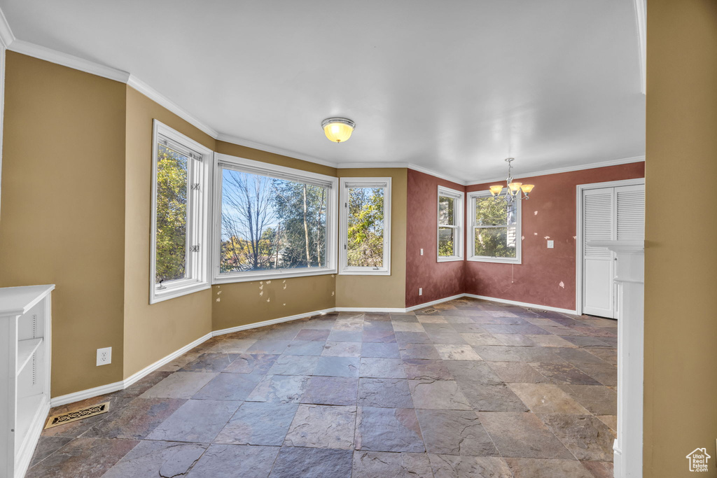 Spare room with plenty of natural light, a chandelier, and crown molding