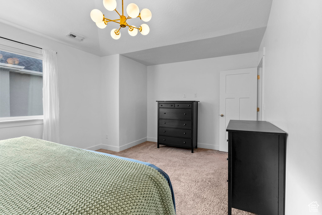 Carpeted bedroom with an inviting chandelier