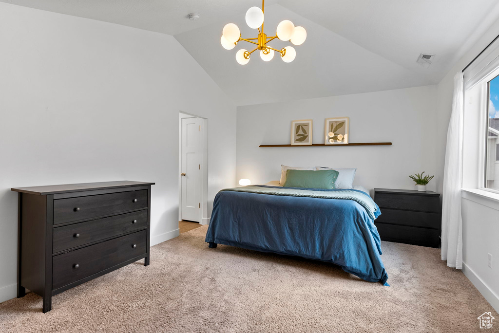 Carpeted bedroom featuring vaulted ceiling and a notable chandelier