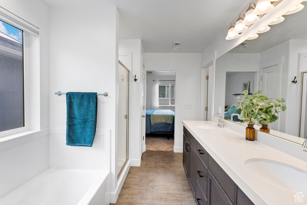 Bathroom featuring wood-type flooring, vanity, and shower with separate bathtub