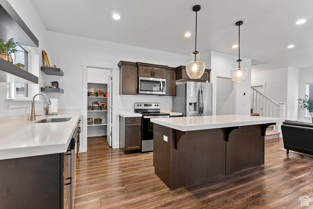 Kitchen with appliances with stainless steel finishes, sink, a kitchen bar, and dark hardwood / wood-style floors