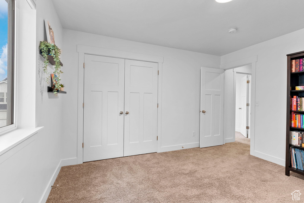 Unfurnished bedroom featuring light carpet and a closet