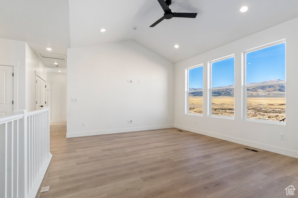 Spare room with a mountain view, light hardwood / wood-style flooring, ceiling fan, and vaulted ceiling