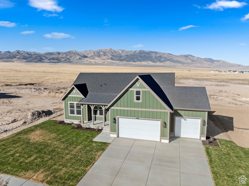 View of front of home featuring a front lawn, a mountain view, and a garage