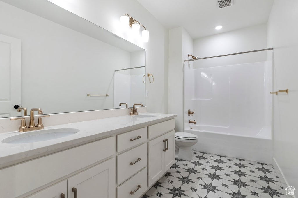Full bathroom featuring toilet, vanity, and shower / washtub combination