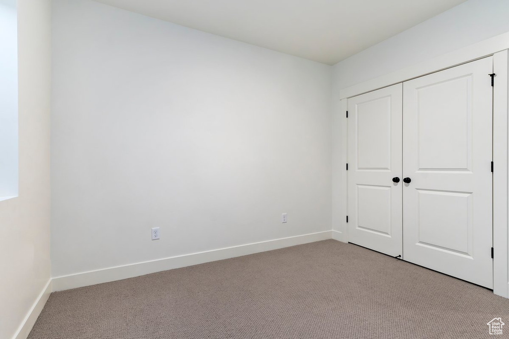 Unfurnished bedroom featuring light carpet and a closet
