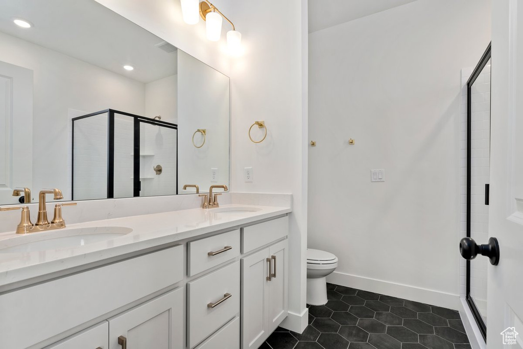 Bathroom featuring vanity, tile patterned flooring, toilet, and an enclosed shower