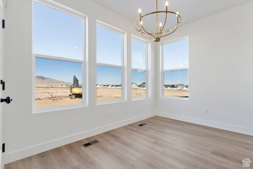 Spare room featuring light hardwood / wood-style floors, a chandelier, and a mountain view
