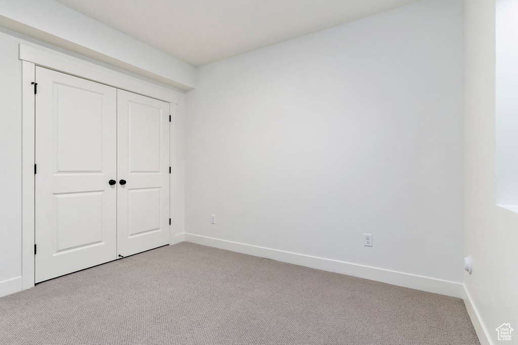 Unfurnished bedroom featuring light colored carpet and a closet