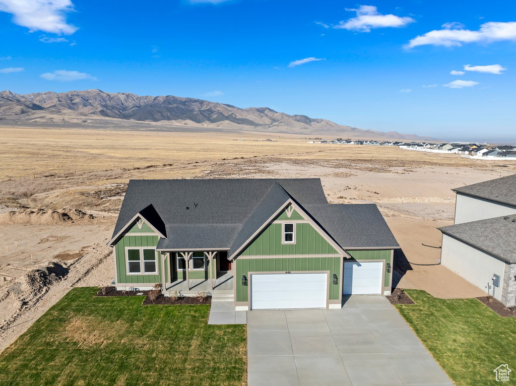 View of front of home featuring a mountain view, a front yard, and a garage
