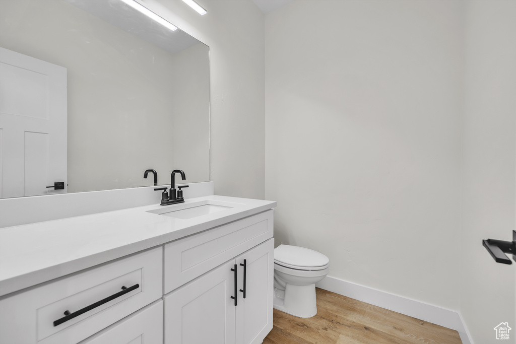 Bathroom with baseboards, wood finished floors, vanity, and toilet