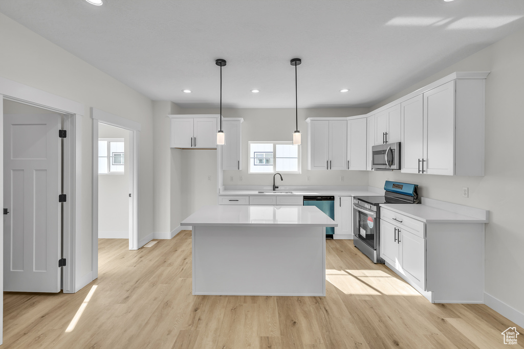 Kitchen featuring white cabinets, a sink, light wood-type flooring, baseboards, and appliances with stainless steel finishes