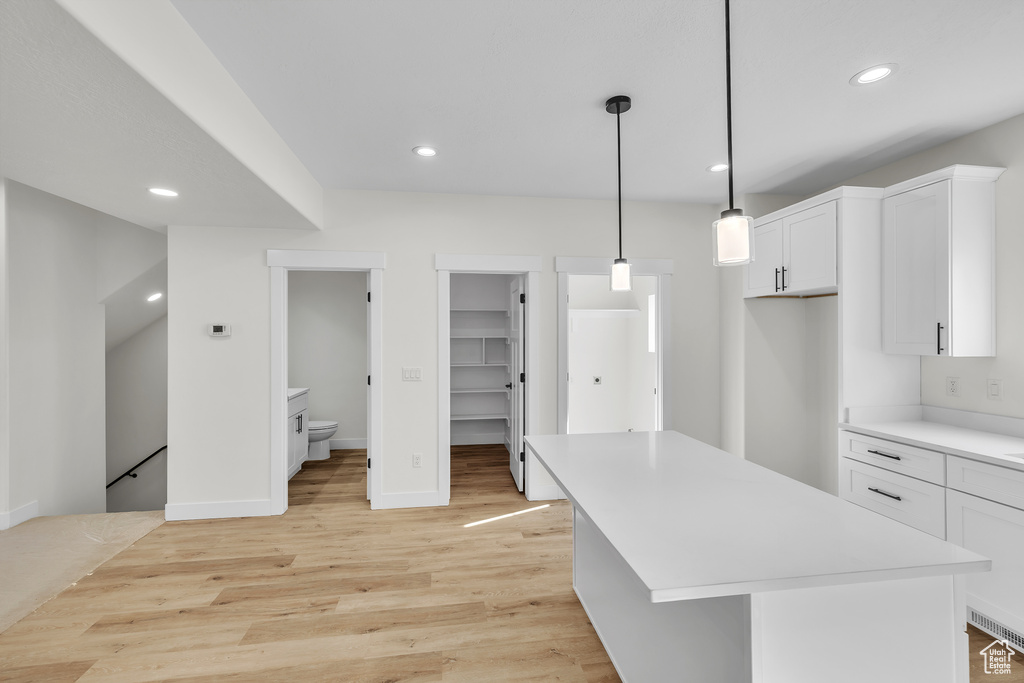 Kitchen with light countertops, light wood-type flooring, white cabinetry, and recessed lighting