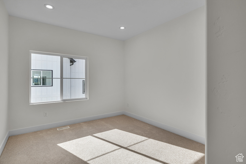 Carpeted empty room with baseboards, visible vents, and recessed lighting