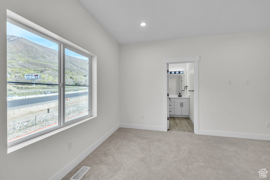 Unfurnished bedroom featuring recessed lighting, visible vents, connected bathroom, baseboards, and light colored carpet