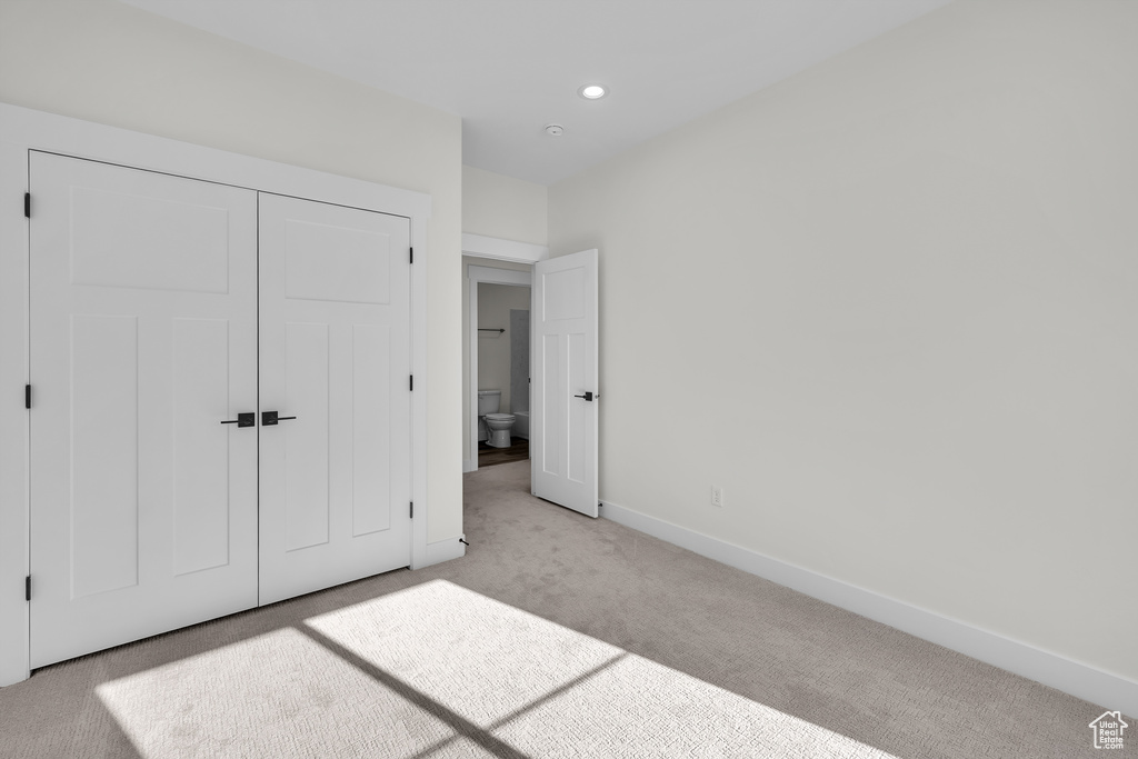 Unfurnished bedroom featuring light carpet, baseboards, recessed lighting, and a closet