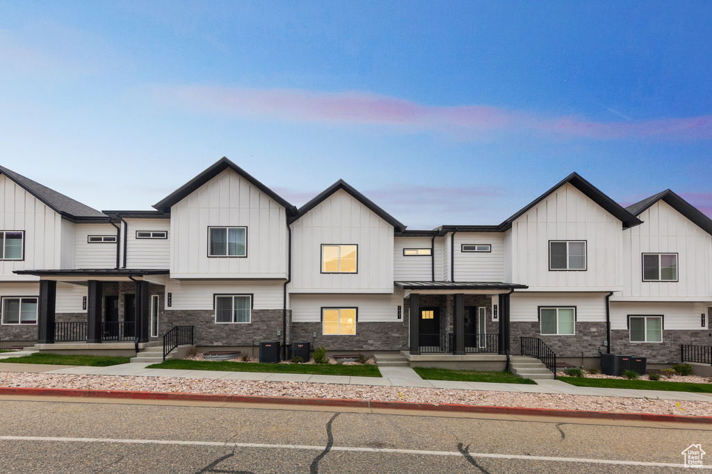 Multi unit property with board and batten siding, cooling unit, a porch, and stone siding