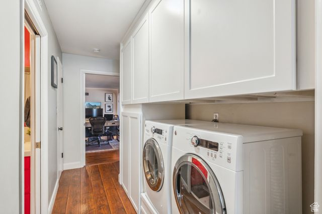 Clothes washing area with cabinets, separate washer and dryer, and dark hardwood / wood-style flooring