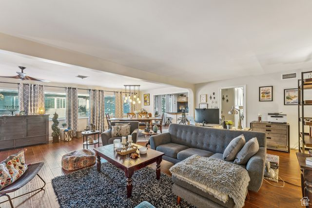 Living room featuring dark wood-type flooring and ceiling fan with notable chandelier