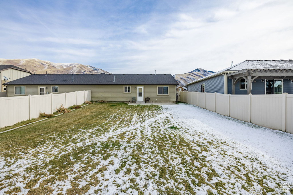 Snow covered house featuring a mountain view and a lawn