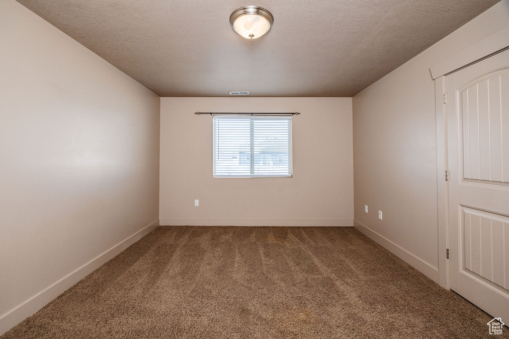 Empty room with carpet flooring and a textured ceiling
