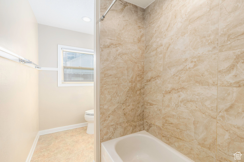 Bathroom with tiled shower / bath and toilet