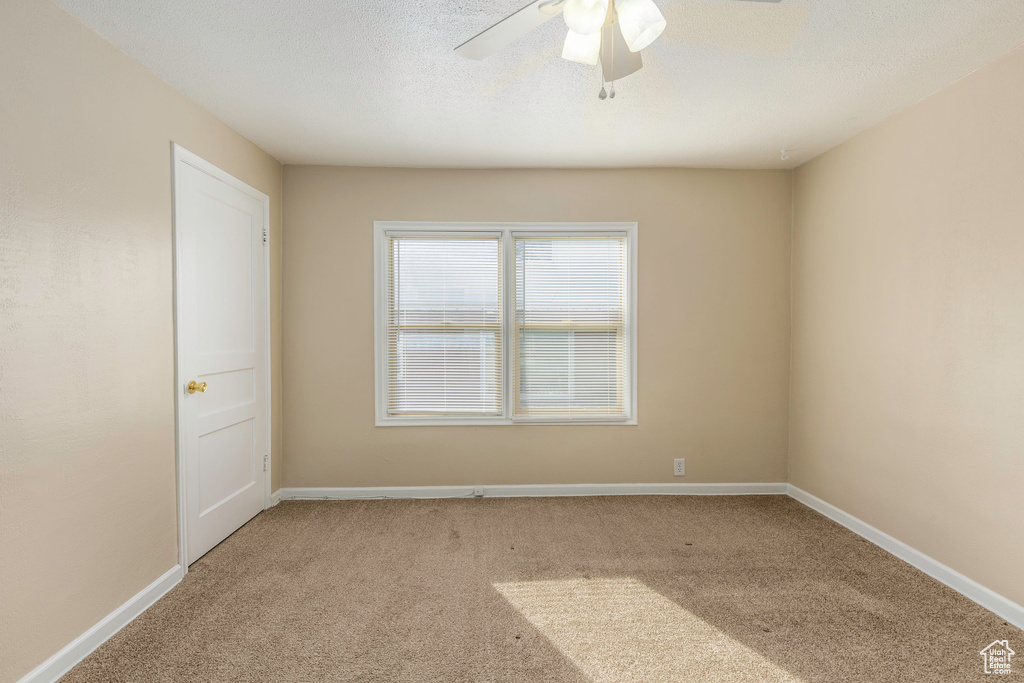 Carpeted spare room with a textured ceiling and ceiling fan