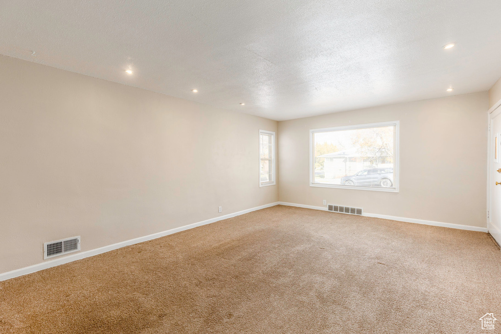 Empty room with carpet floors and a textured ceiling