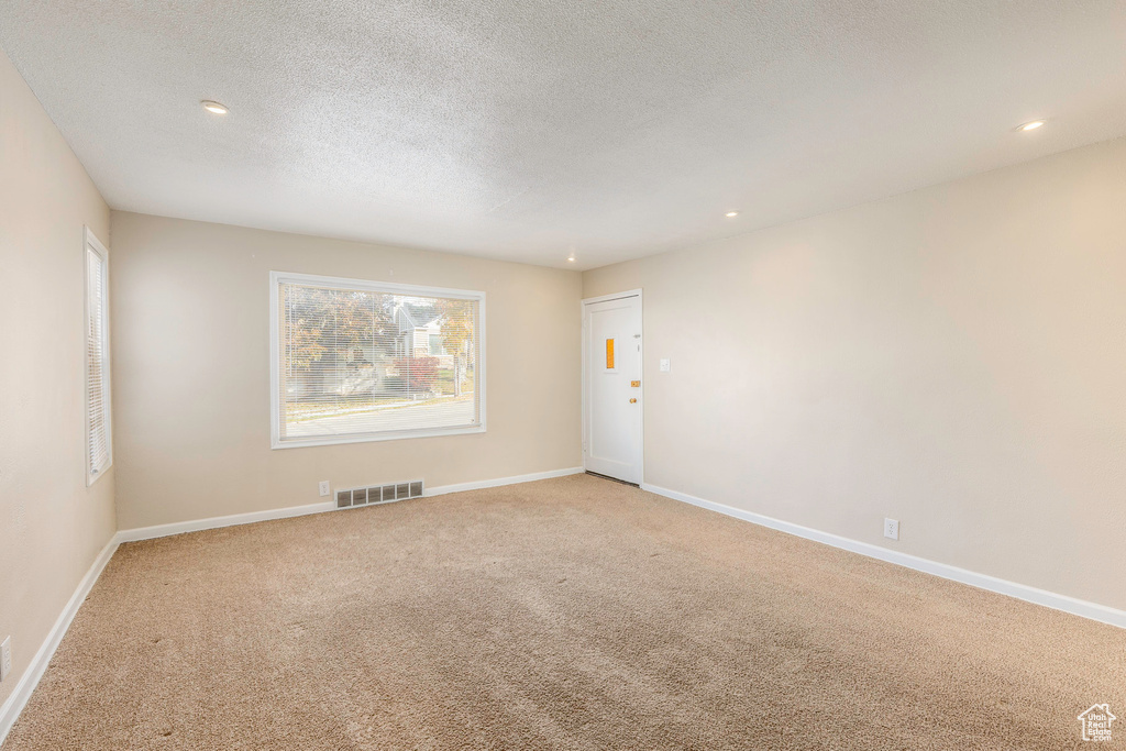 Carpeted spare room with a textured ceiling