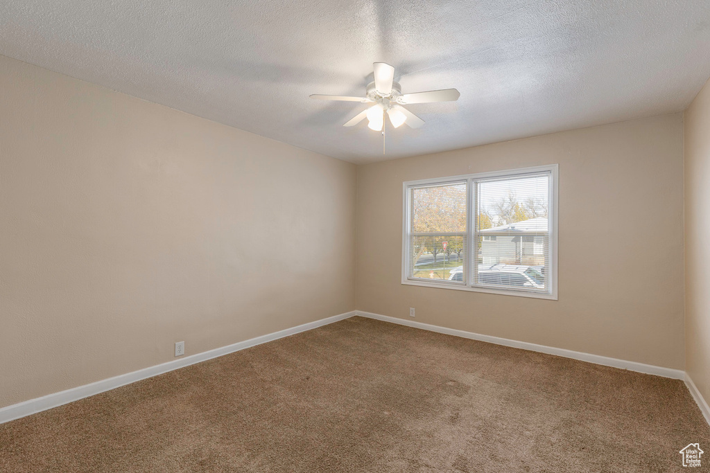 Carpeted spare room with ceiling fan and a textured ceiling