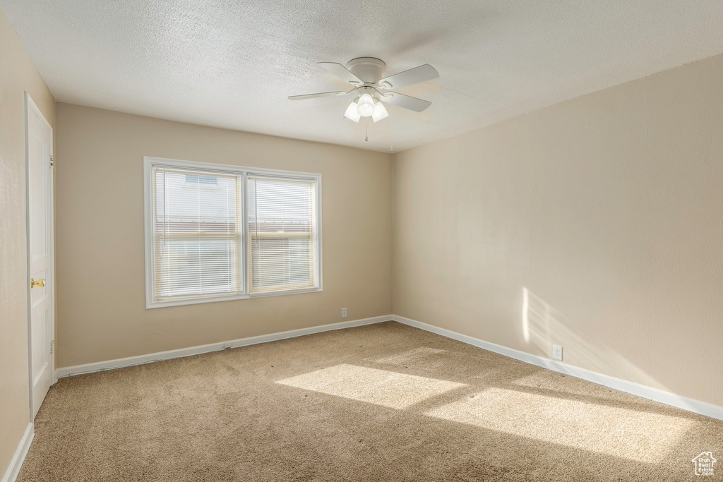 Carpeted spare room with a textured ceiling and ceiling fan