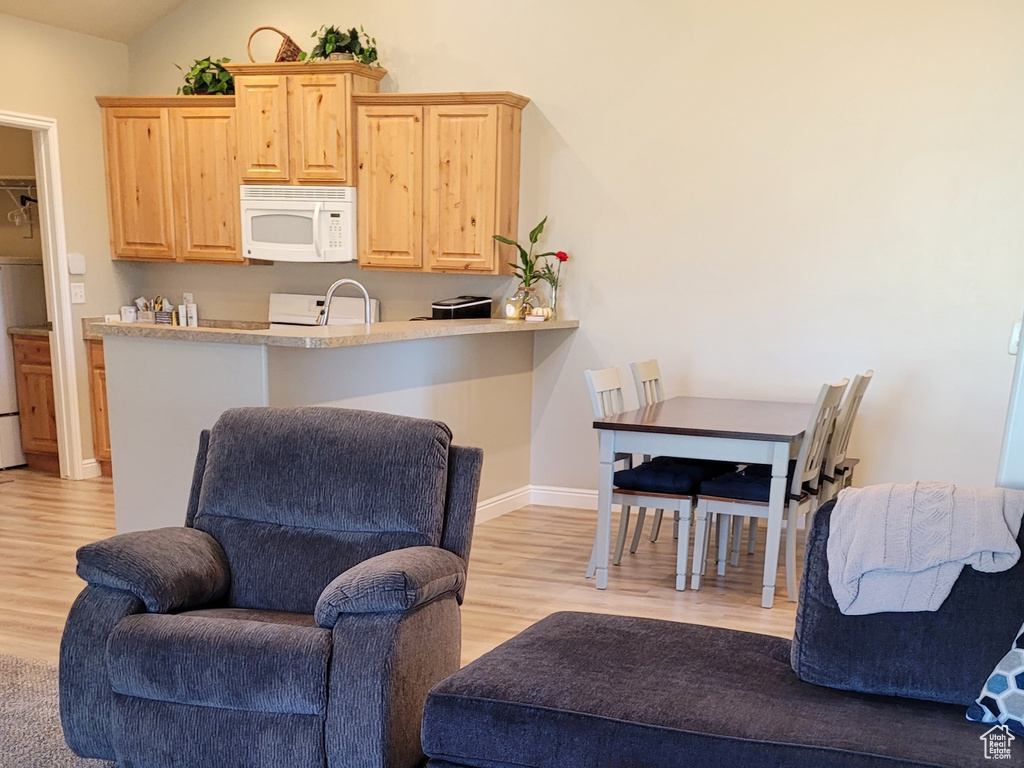 Living room featuring washer / dryer, sink, light wood-type flooring, and high vaulted ceiling