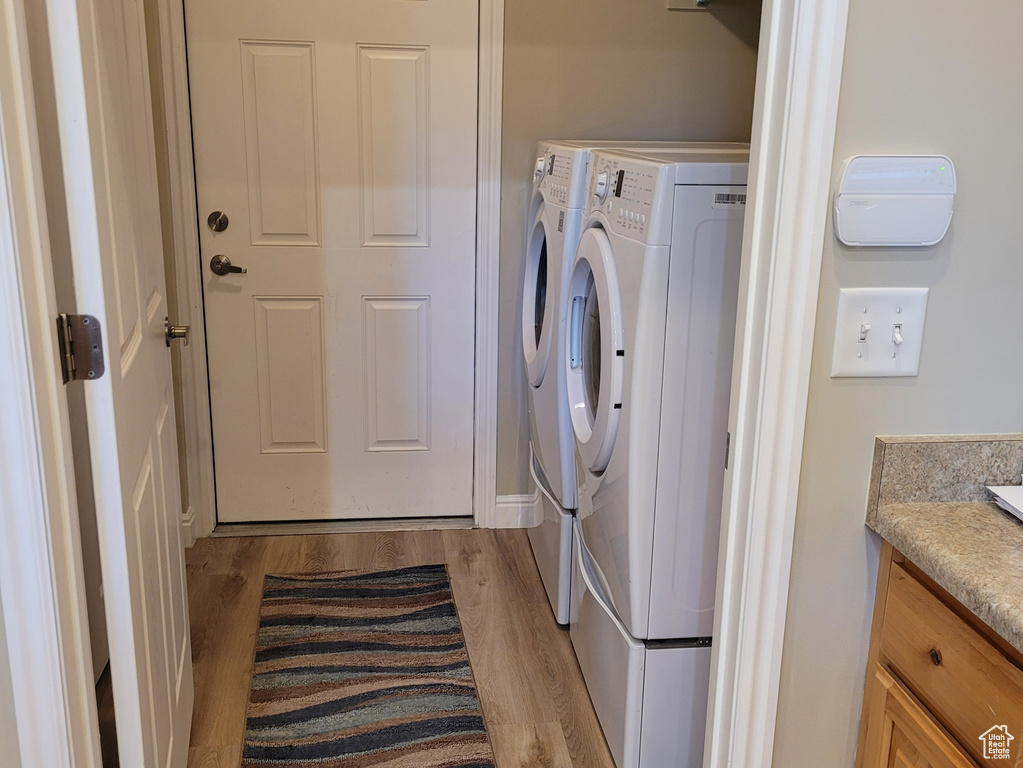 Washroom with light wood-type flooring and washer and dryer