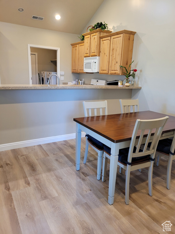 Dining space with washer and dryer, sink, light wood-type flooring, and vaulted ceiling