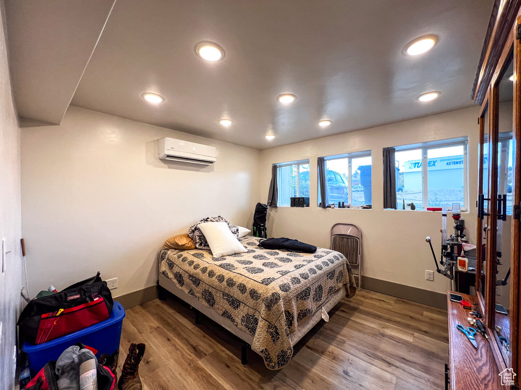 Bedroom with hardwood / wood-style floors and an AC wall unit