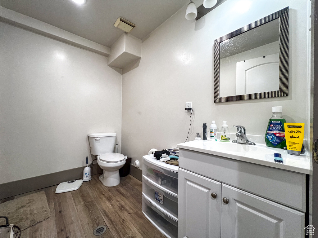 Bathroom with hardwood / wood-style floors, vanity, and toilet