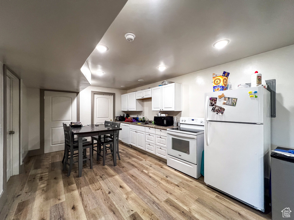 Kitchen featuring white cabinets, white appliances, sink, and light hardwood / wood-style floors