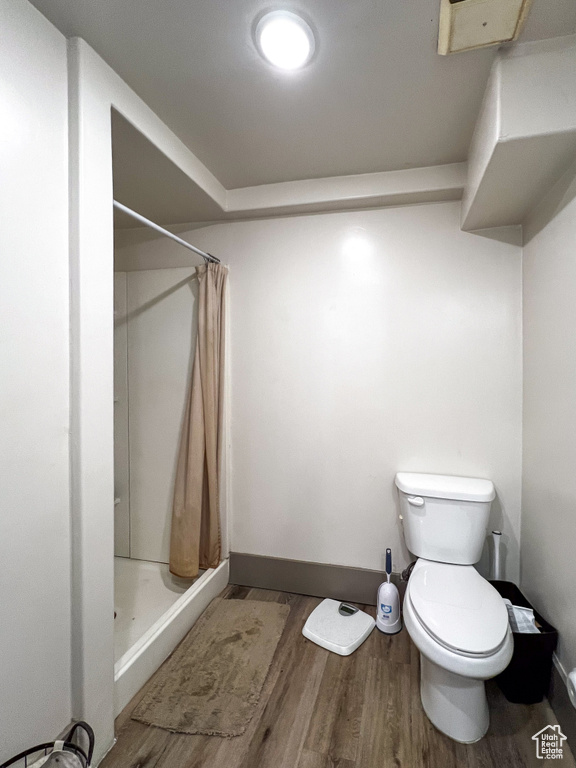 Bathroom featuring hardwood / wood-style floors, toilet, and a shower with curtain