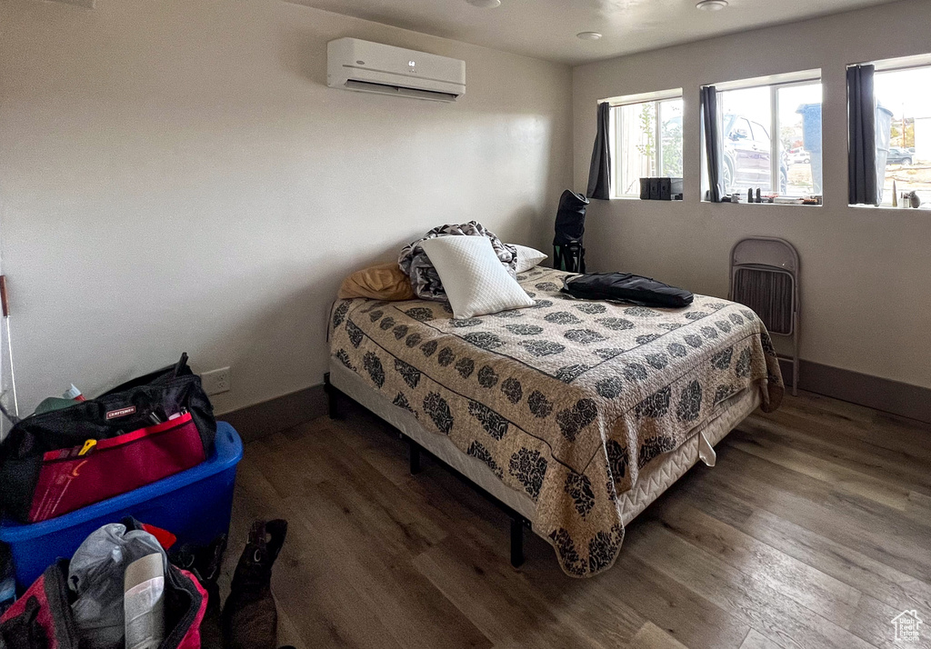 Bedroom featuring dark hardwood / wood-style flooring and a wall mounted air conditioner