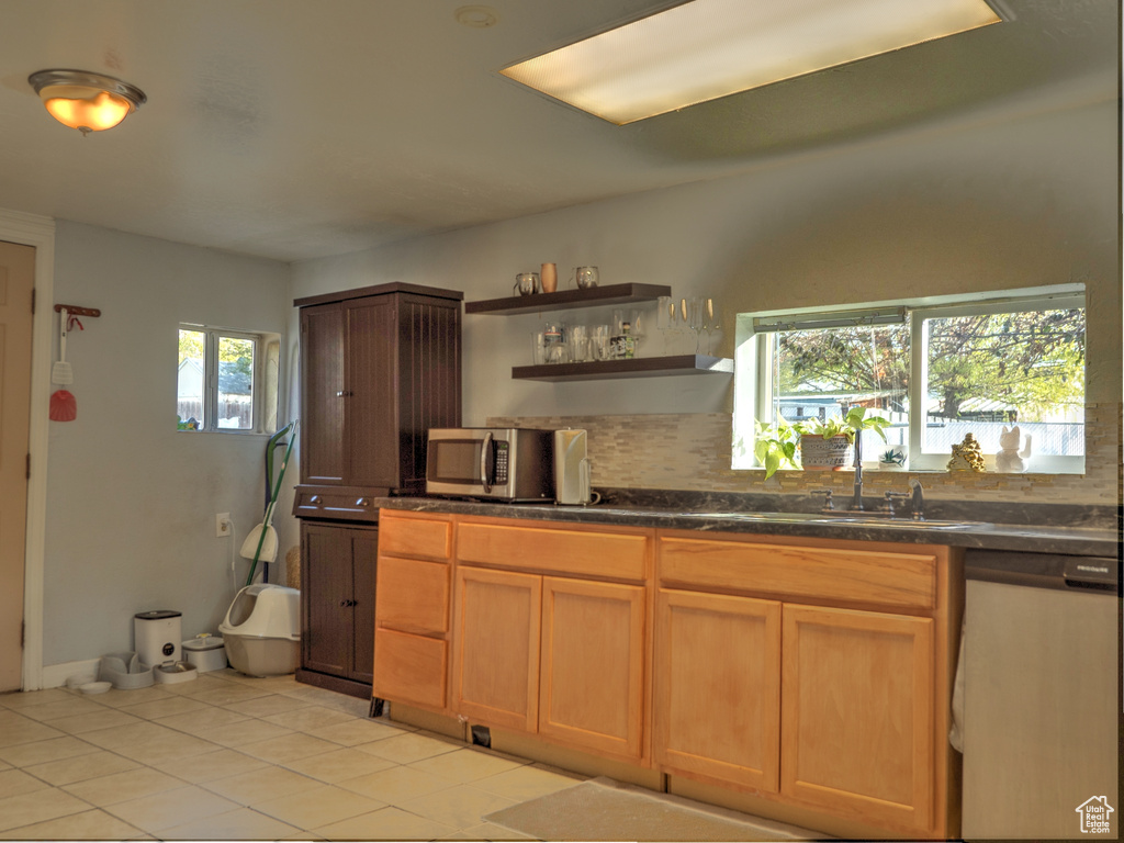 Kitchen with a wealth of natural light, appliances with stainless steel finishes, and light tile patterned flooring