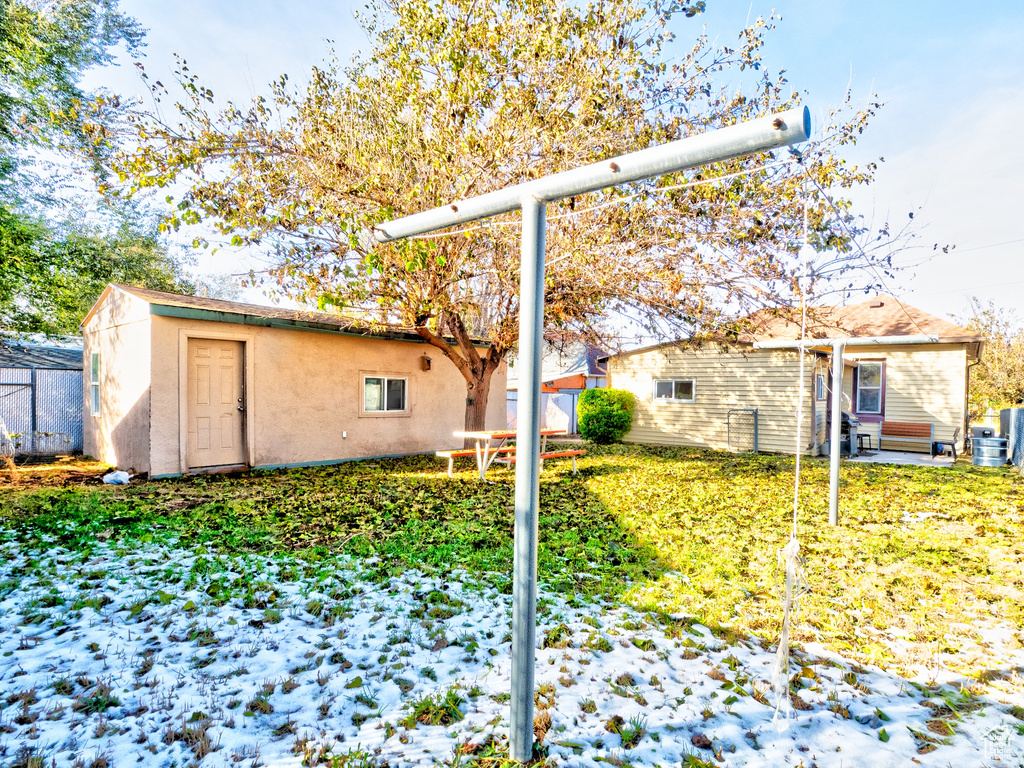 Snow covered house featuring a storage shed and a yard