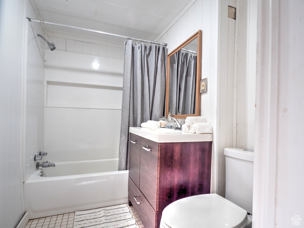 Full bathroom featuring toilet, wood walls, vanity, and shower / tub combo