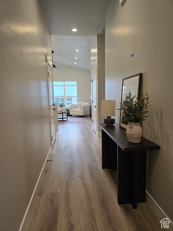 Hallway with wood-type flooring and lofted ceiling