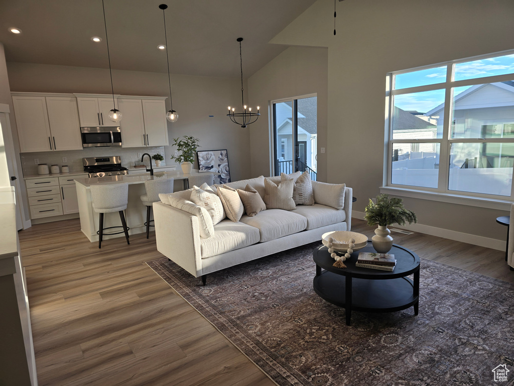 Living room with a chandelier, dark hardwood / wood-style floors, lofted ceiling, and sink
