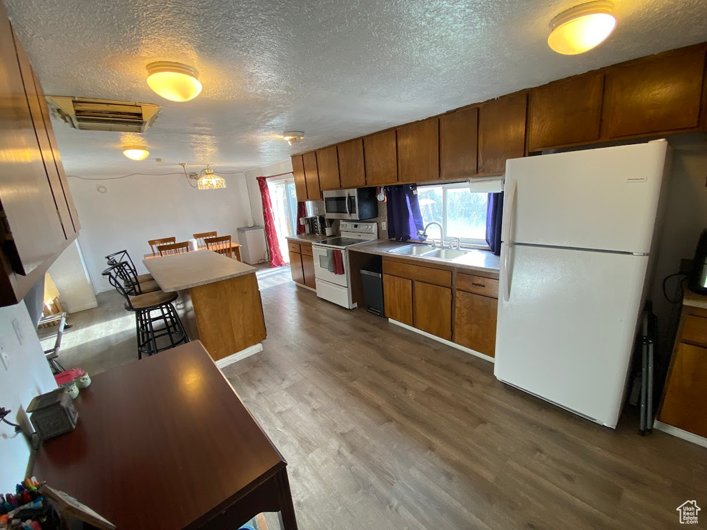 Kitchen with a textured ceiling, dark hardwood / wood-style floors, white appliances, and sink