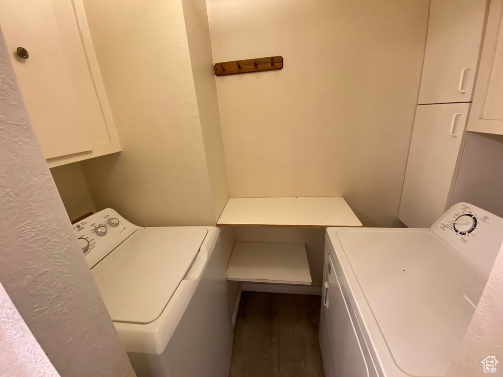 Washroom with dark hardwood / wood-style flooring and washer / dryer