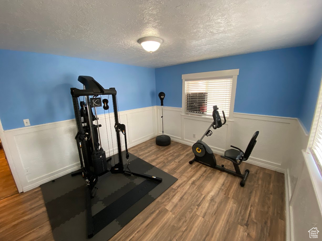 Exercise room featuring a textured ceiling and dark wood-type flooring