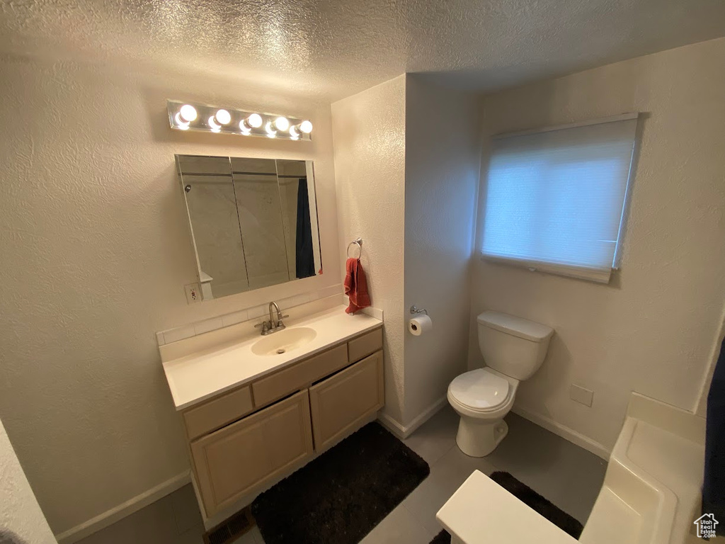 Bathroom featuring vanity, curtained shower, toilet, and a textured ceiling